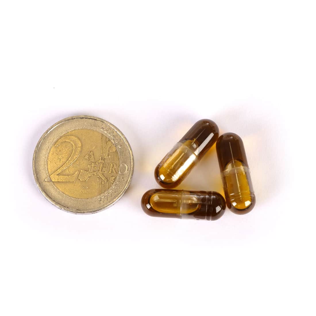 Drie Medihemp CBD-capsules 5% (25 mg) naast een euromunt op een witte achtergrond.